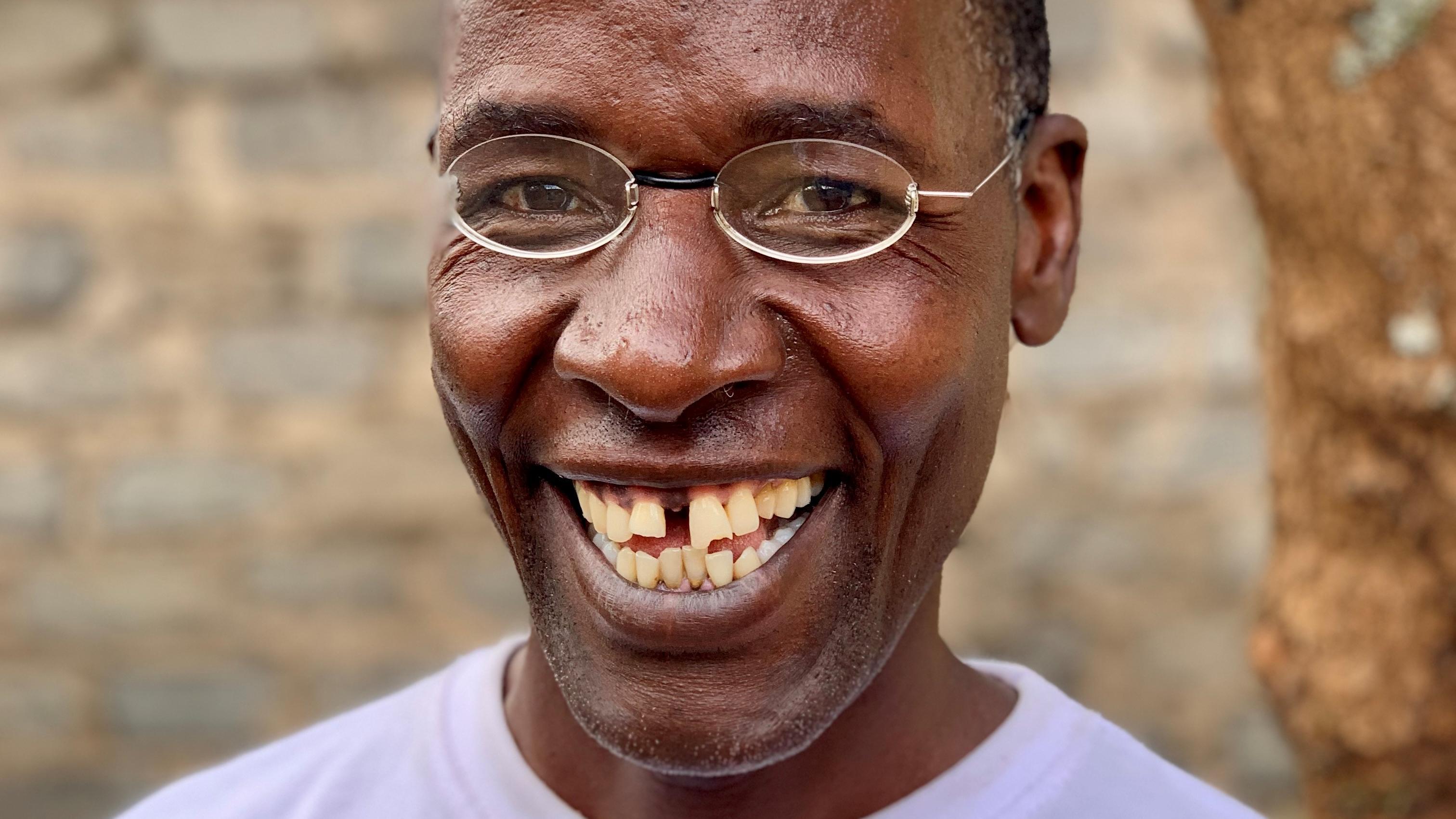 Kenyan man laughing in front of tree