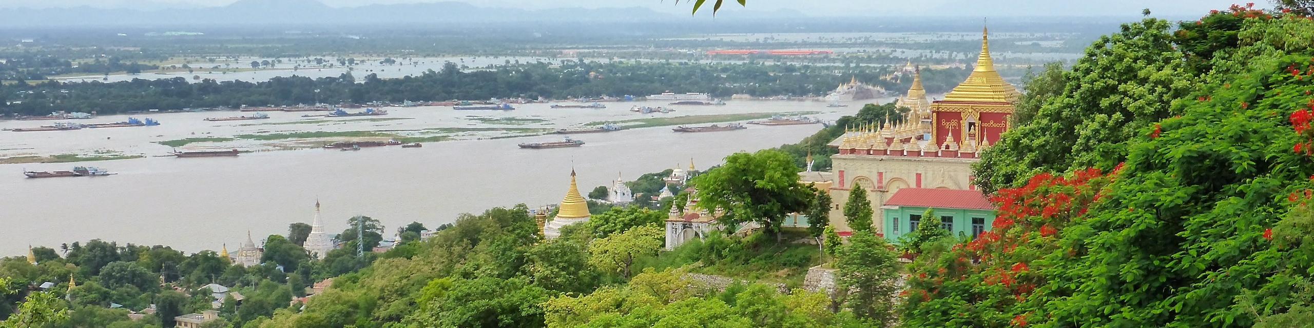 Panorama in Myanmar, grüne Wälder, Tempel mit goldenen Dächern, Fluss im Hintergrund