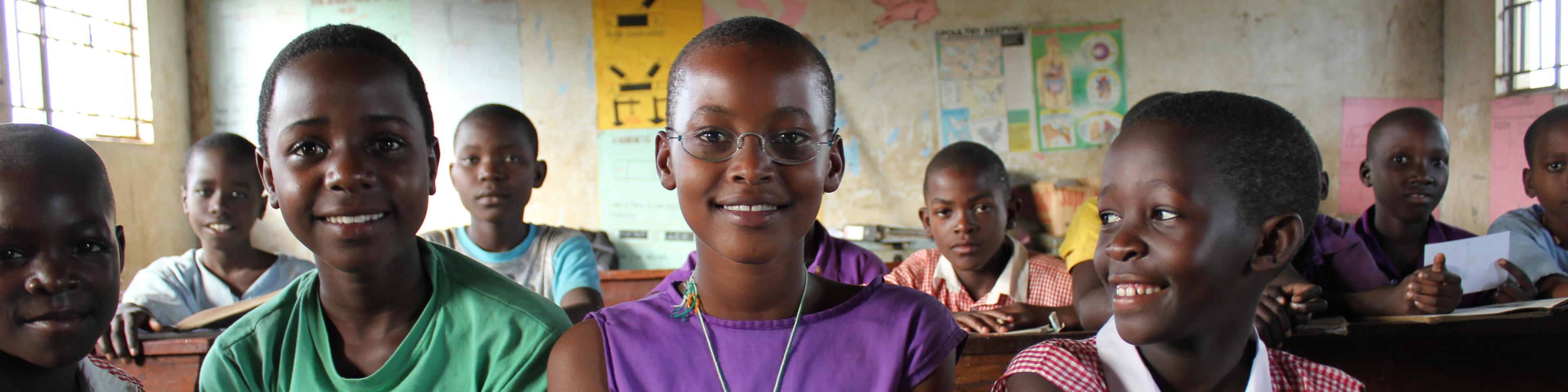 Schülerinnen aus Uganda im Klassenzimmer, eine trägt EinDollarBrille