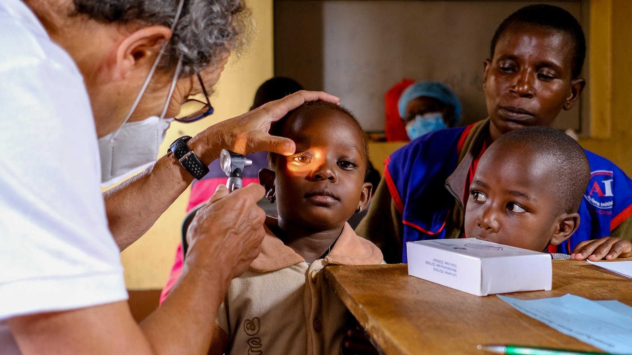 An ophthalmologist shines a light into a child's eye