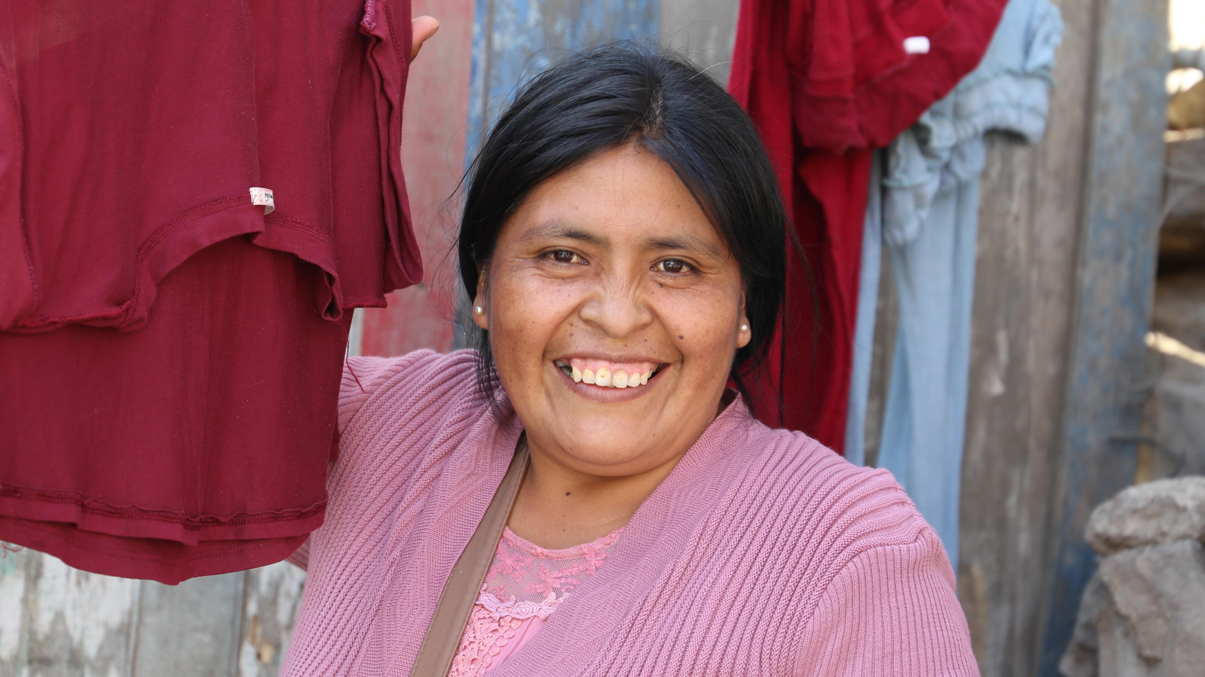 Peruanische Frau vor Wäscheleine mit roter Kleidung