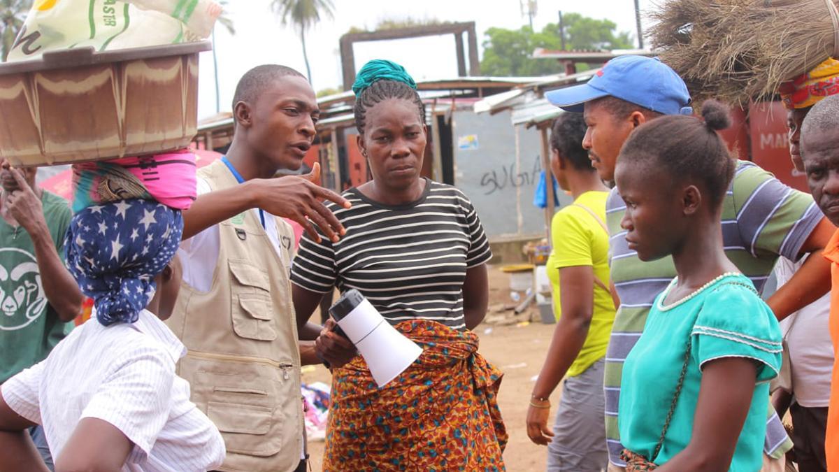 Mitarbeiter von GoodVision Liberia spricht mit Leuten auf dem Markt, macht auf EinDollarBrille aufmerksam