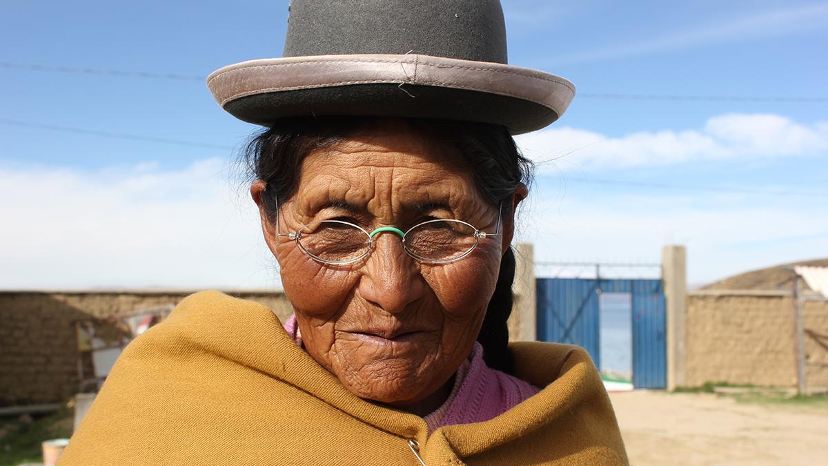 Traditionell gekleidete Frau in Bolivien, mit Hut, trägt EinDollarBrille