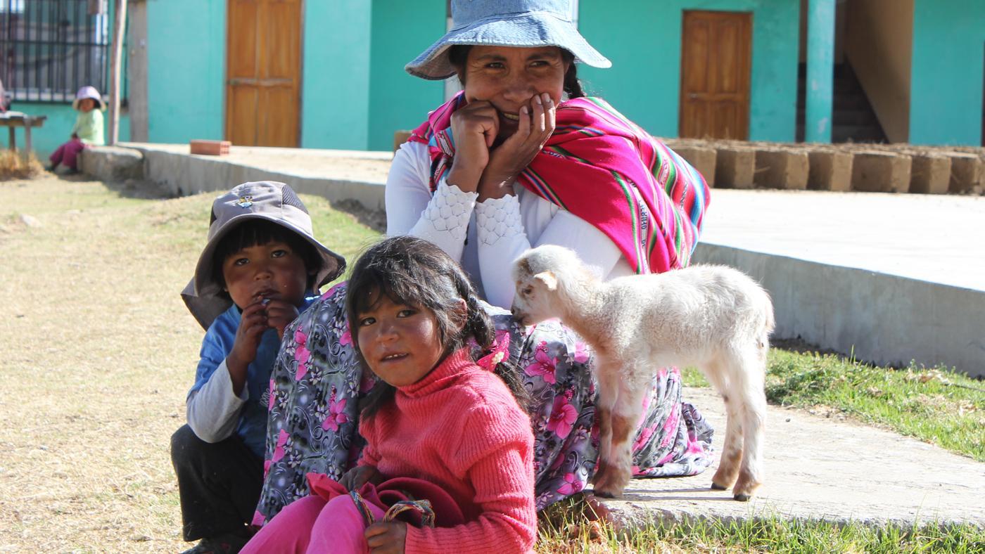 Eine bolivianische Frau mit zwei Kindern und einem Lamm