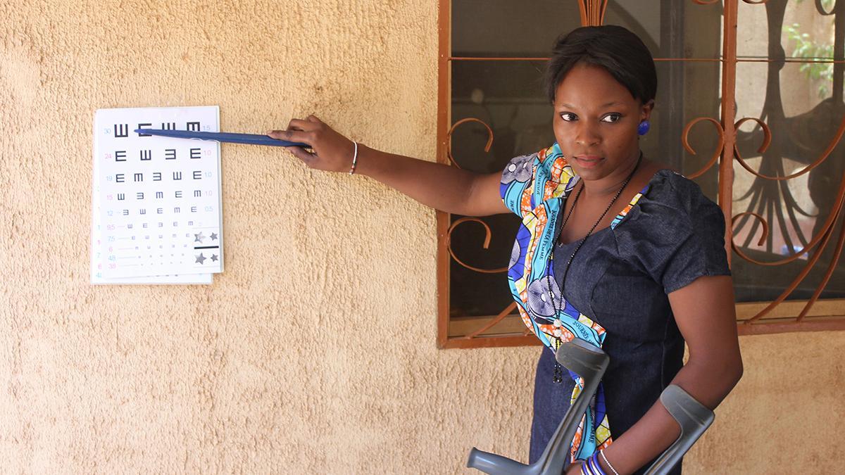 Mitarbeiterin von GoodVision Burkina Faso zeigt an der Sehprobentafel