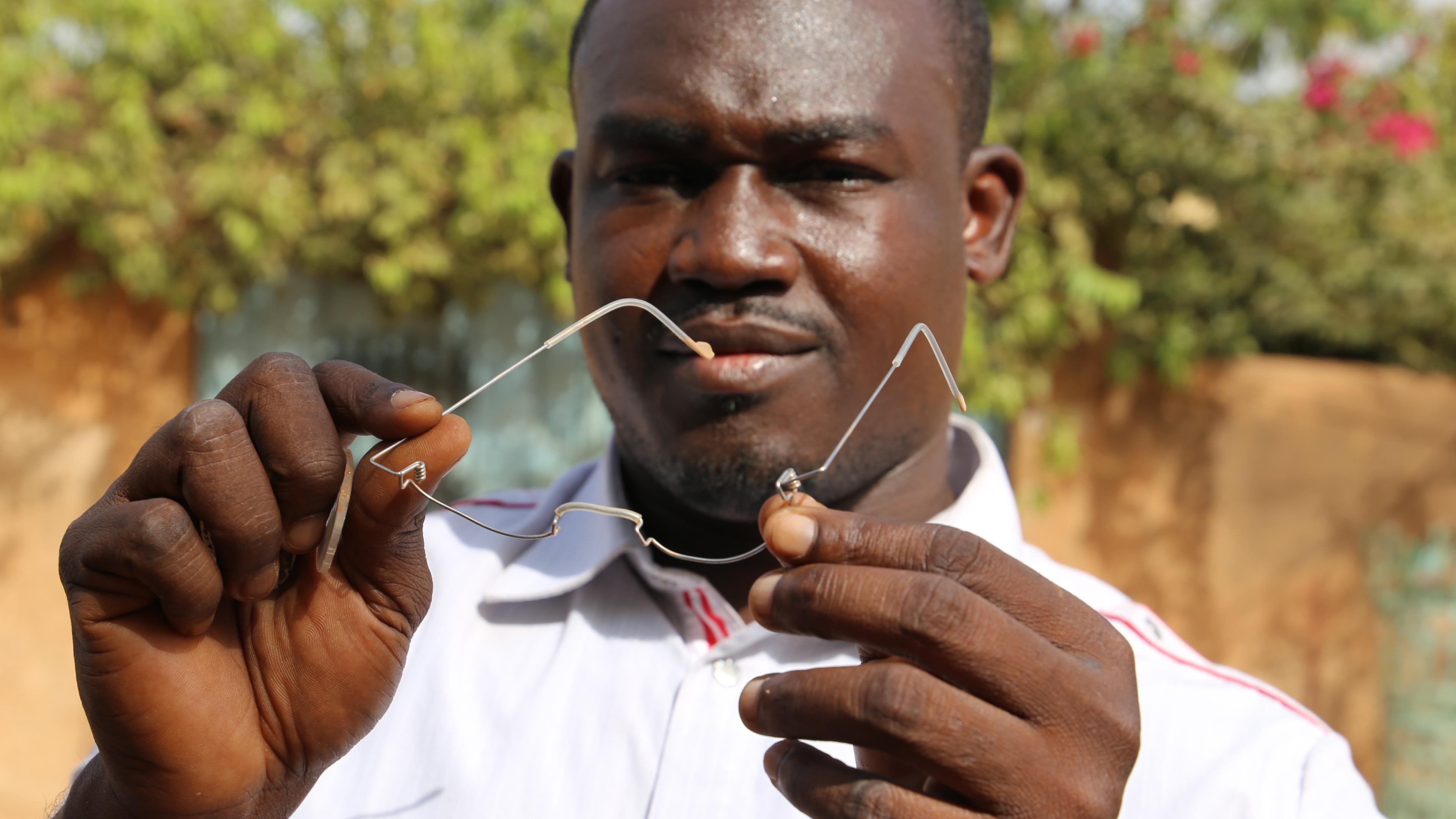 GoodVision Burkina Faso employee holds bent OneDollarGlasses