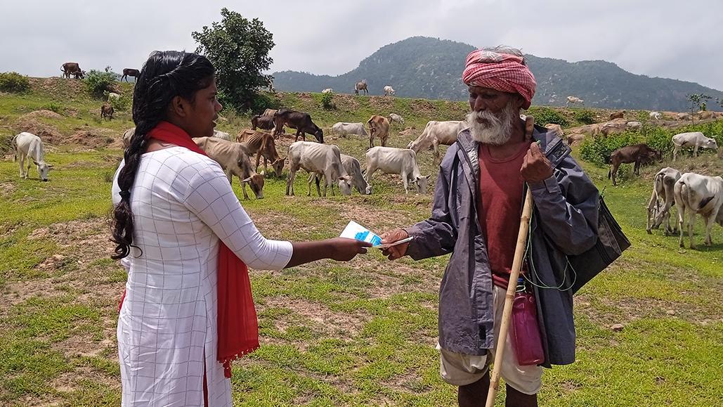 Woman hands flyer to a cowherd