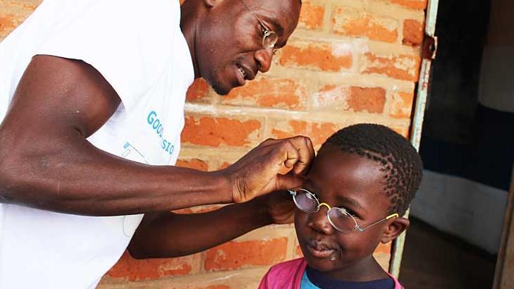 Mitarbeiter von GoodVision Malawi passt einem Mädchen die EinDollarBrille an