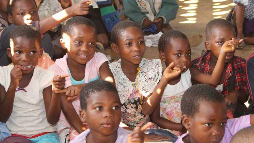 Schüler einer Klasse in Malawi geben mit der Hand Richtung an