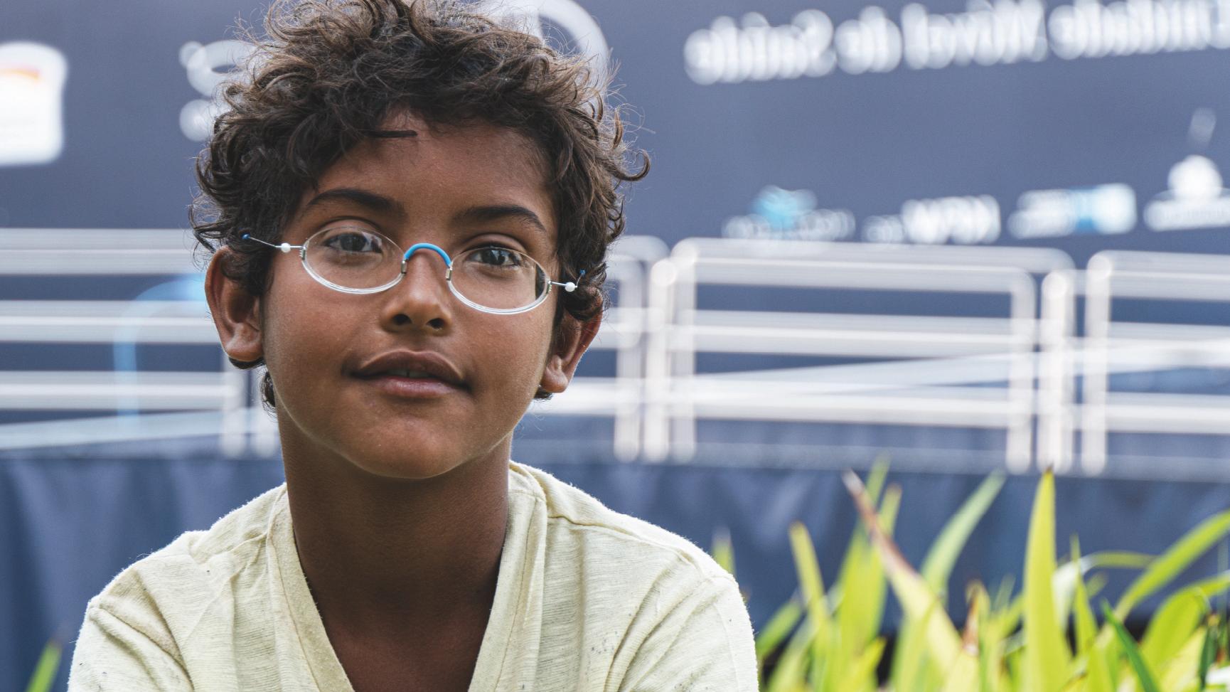 Brasilianischer Junge mit Brille vor blauem LKW