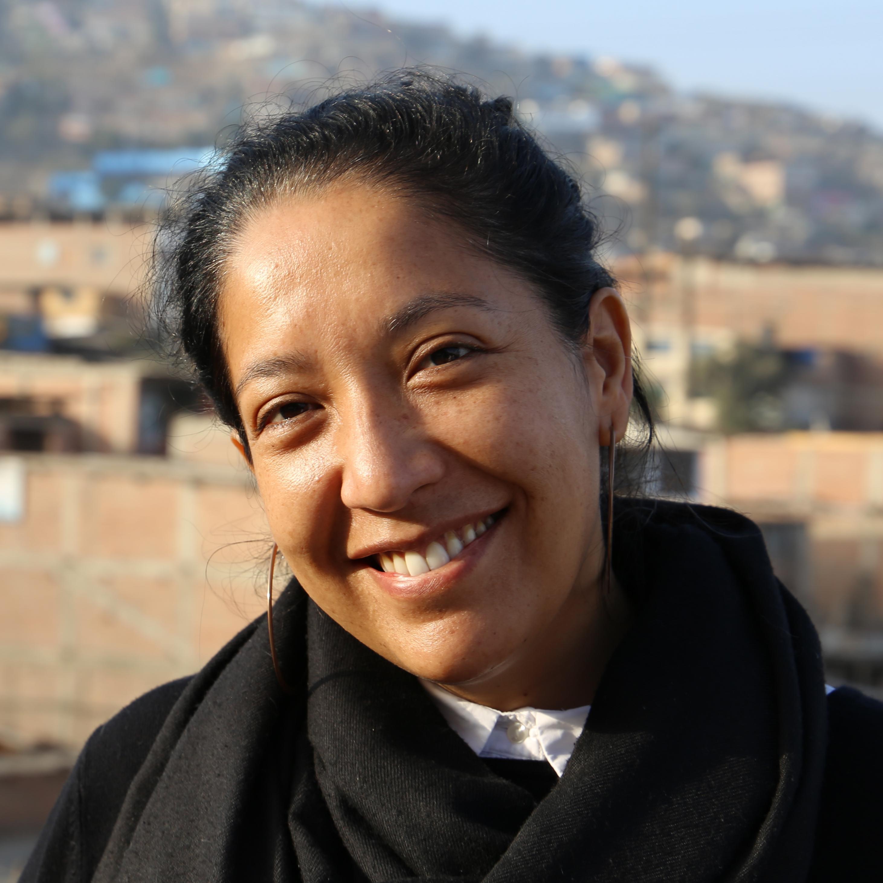 Peruanische Frau steht vor den Berghängen der Pueblos Jovenes in Lima