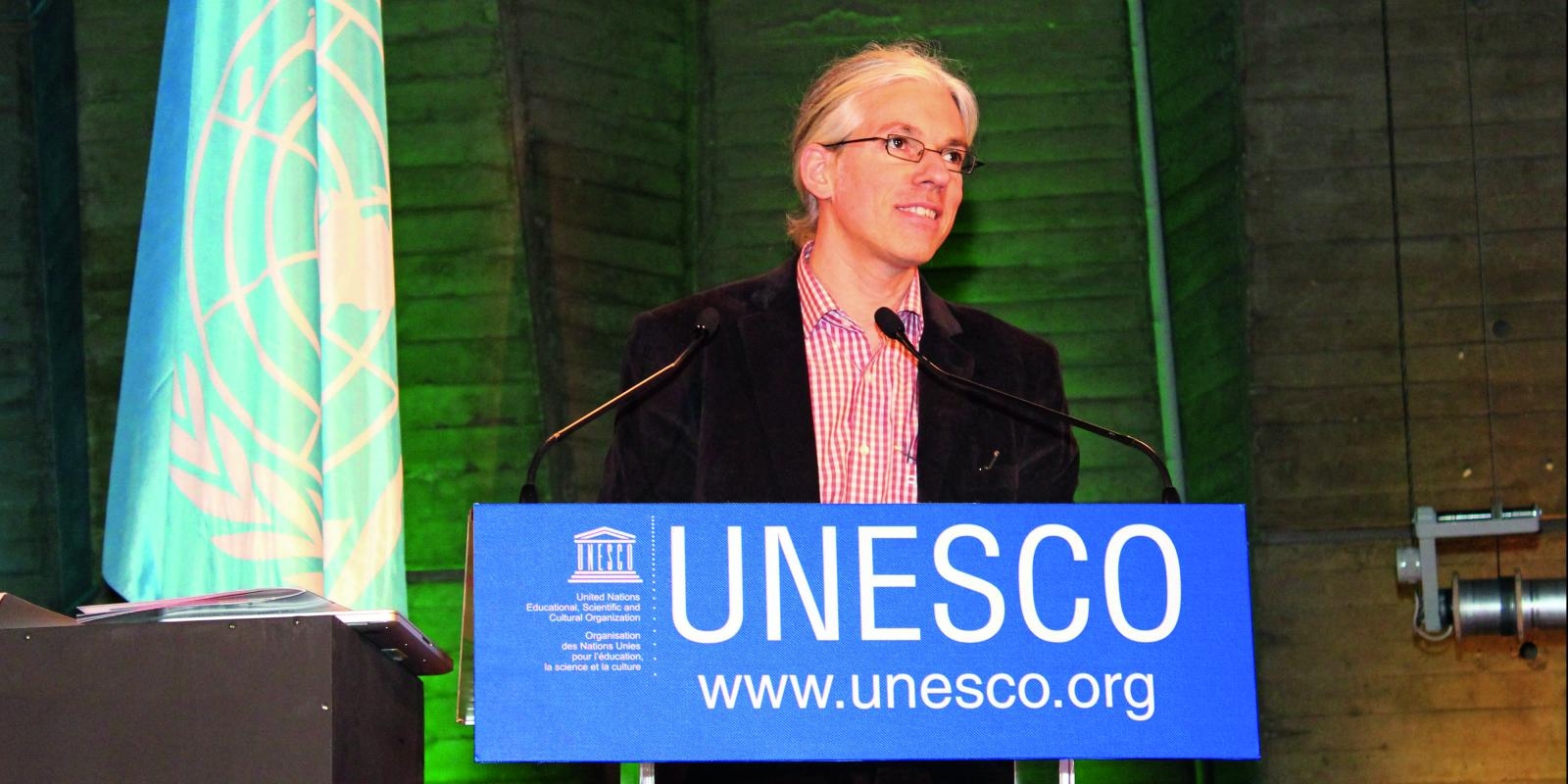 Martin Aufmuth stands at a lectern in front of UNESCO in Paris