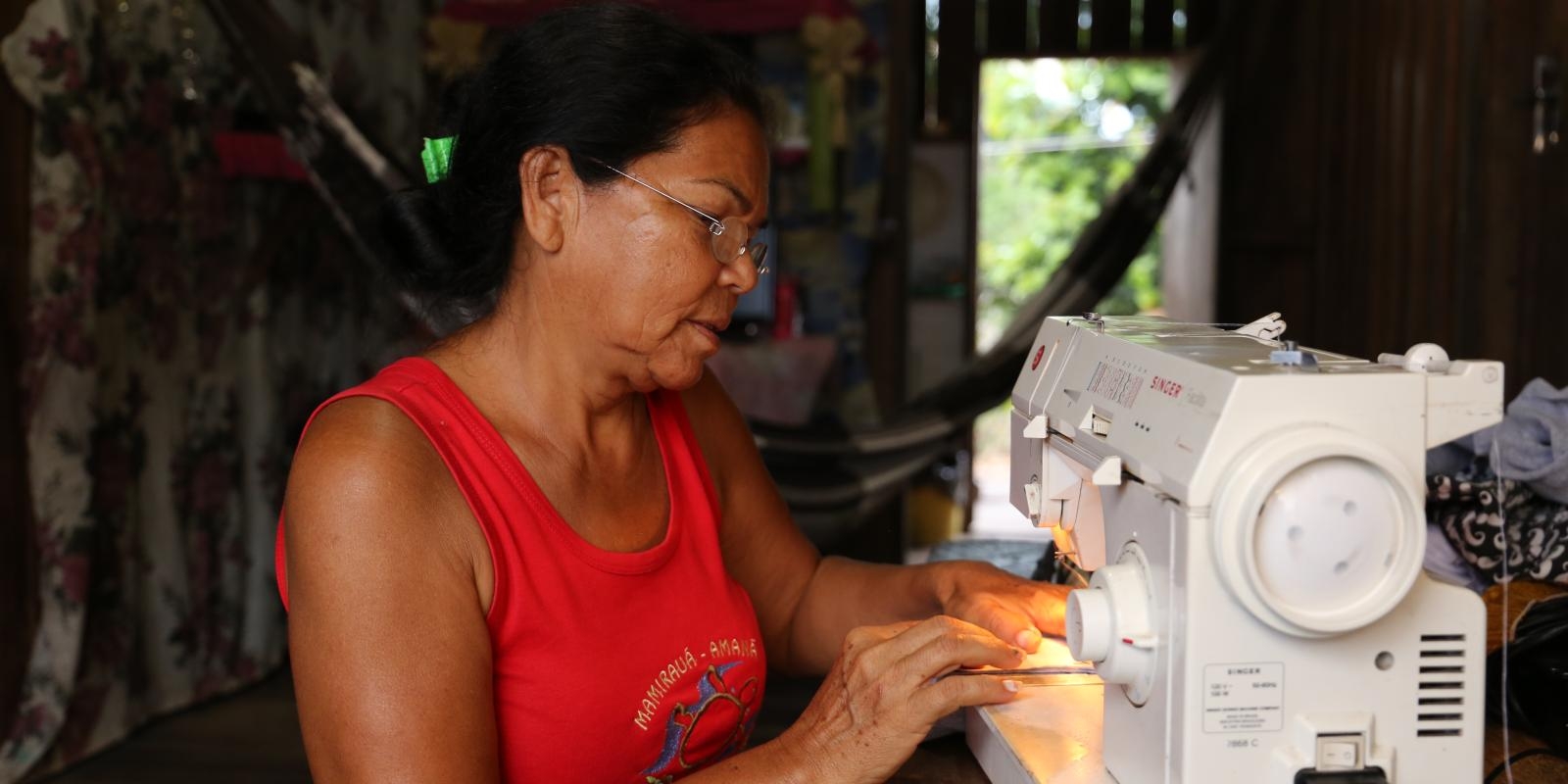 Frau aus Bolivien sitzt an Nähmaschine