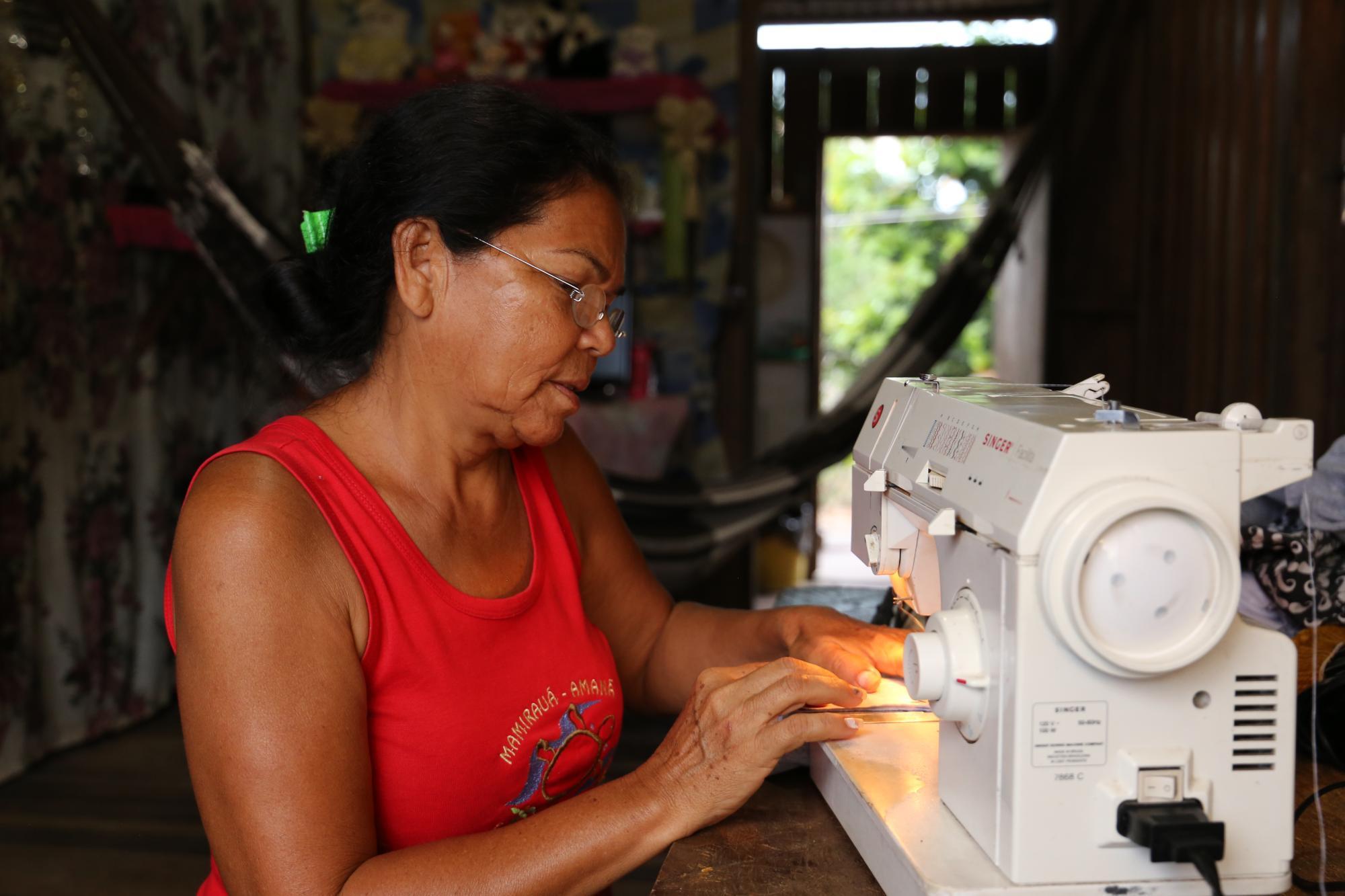 Frau aus Bolivien sitzt an Nähmaschine