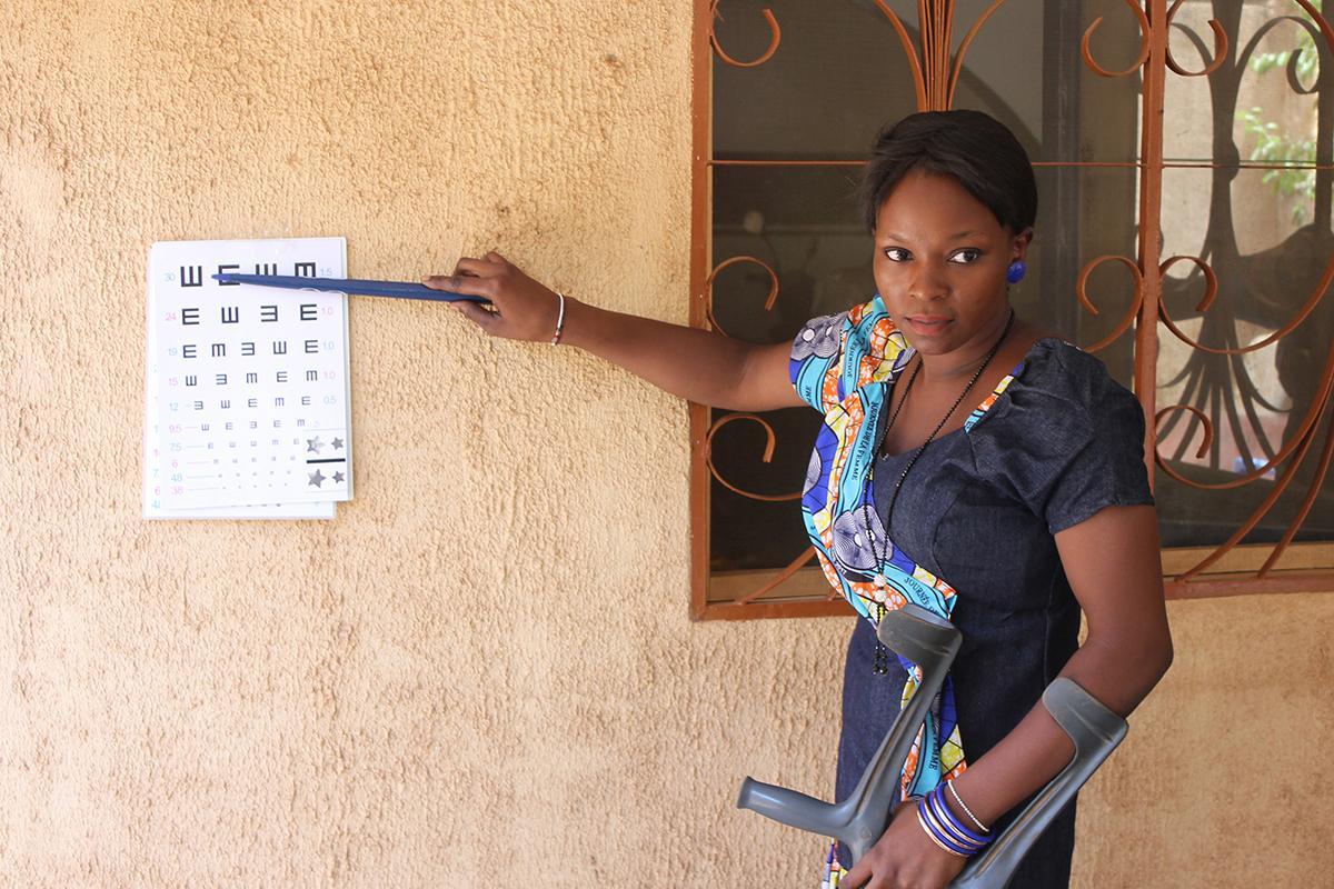 Mitarbeiterin von GoodVision Burkina Faso zeigt an der Sehprobentafel