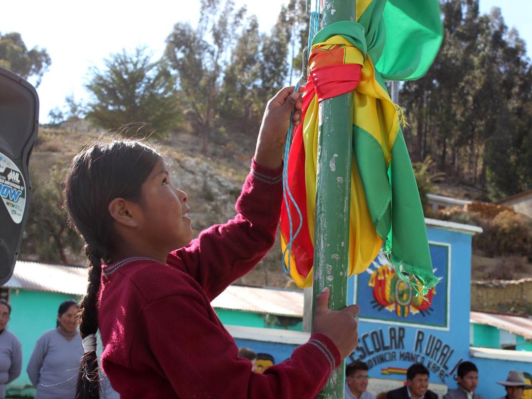 Bolivianische Schülerin hisst eine Fahne