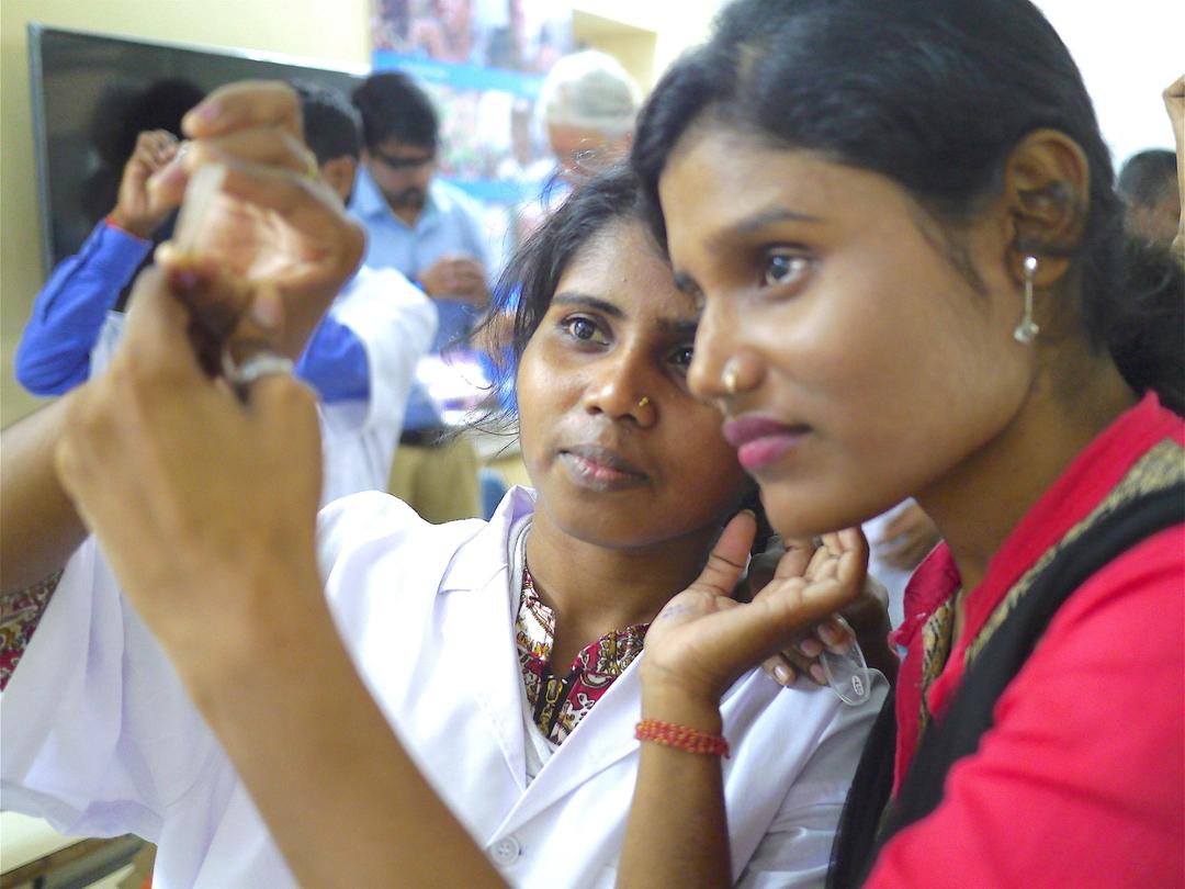 Two Care Netram employees check the lens